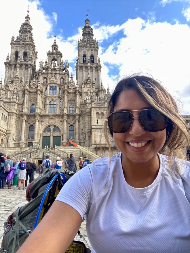 Shirin smiling outside the cathedral in Santiago de Compostela after walking the Camino